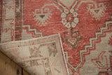 Distressed Oushak rug showing faded red geometric pile and hand-knotted beige foundation.