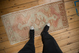 Distressed Oushak runner with abrashed sandalwood, ivory, and silver geometric patterns, seen with feet.