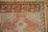 Distressed vintage Oushak rug detail: worn pile, sandalwood, muted red, soft green, geometric border.