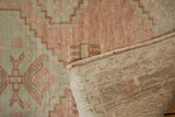 Vintage distressed Oushak rug: Worn pile in sandalwood, copper, and intact side selvage.