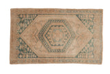 Distressed vintage Oushak rug with concentric hexagonal medallions in dusty jade green and cream.
