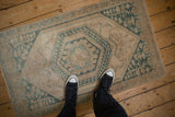 A person's perspective looking down at a vintage distressed Oushak rug with a faded look.