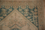 Corner view of a vintage Oushak rug's germinating plant spandrel in dusty jade green with even wear.