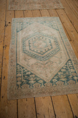 Angled view of a vintage distressed Oushak rug with a green and ivory hexagonal medallion design.