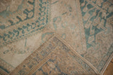 Detail of a distressed Oushak rug's corner showing the hand-knotted foundation and secured side cord.
