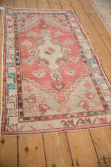 A vintage distressed Oushak runner from an angle, showing its abrashed dusty rose and silver design.