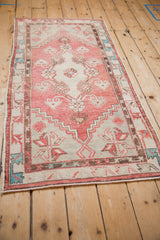 Angled perspective of a vintage distressed Oushak runner in dusty rose, ivory, and turquoise.
