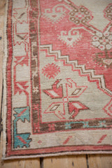 Turquoise and dusty rose accents in the brown meandering border of a distressed Oushak rug.