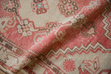 Softly worn texture of a hand knotted Oushak rug with dusty rose and brown geometric florals.