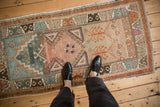 Distressed Oushak rug runner with geometric patterns, heavy abrash, and teal to tangerine color shift.