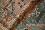Textured pile of a folded Oushak runner showcasing geometric patterns in mauve, teal, and tangerine.