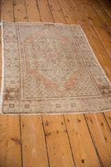 Distressed Oushak rug corner, faded floral medallion and seed motif in pale rust.