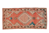 Distressed Oushak runner with a checkered diamond medallion in blush red, ivory, and turquoise.