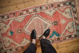 Vintage distressed Oushak runner in blush red and ivory viewed from above to show its scale.