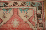 Geometric corner spandrel of a distressed Oushak rug in blush red, turquoise, and chocolate brown.