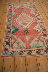 Angled view of a distressed Oushak runner highlighting its blush red diamond medallion.