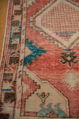 Detail of geometric patterns in blush red, turquoise, and brown on a distressed Oushak runner.