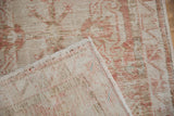 A folded corner of the distressed Oushak rug reveals the hand-knotted construction on its reverse.