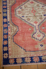 Abrashed dusty rose field beside the cobalt blue floral border of a vintage distressed Oushak rug.