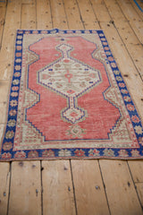 A distressed vintage Oushak rug from an angle, highlighting its stepped medallion and cobalt border.