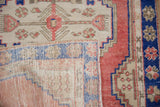 The hand-knotted foundation and distressed pile of a vintage Oushak rug's folded corner.
