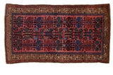Vintage Kurdish Hamadan rug with stylized ram's horn guls in blue and teal on a faded raspberry red field.