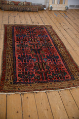 Angled view of a vintage Kurdish Hamadan rug showing its full geometric pattern and borders.