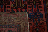 A folded corner on the vintage Kurdish rug displays its hand-knotted wool pile and woven back.