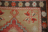 Corner detail of a distressed Oushak rug with a floral border and stepped red spandrel.