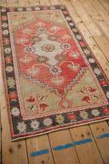 Angled perspective on a distressed Oushak rug, showing its faded red field and ivory geometric medallion.