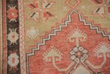 A stepped corner spandrel in faded red on a distressed Oushak rug with low, even wear.