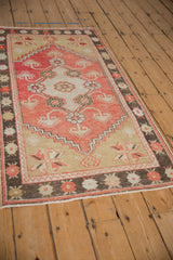 A distressed vintage Oushak rug in faded brick red, beige, and charcoal, shown at a high angle.