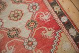 Worn texture of a distressed Oushak rug's faded brick red field and charcoal floral border.