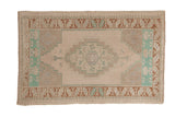 Distressed vintage Oushak rug with a stepped medallion in soft ivory, copper brown, and pale turquoise.