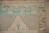 Corner detail of a vintage Oushak rug featuring a pale turquoise geometric border and soft, worn pile.