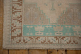 Detail of a distressed Oushak's corner, showing the soft, even wear and copper-brown geometric border.