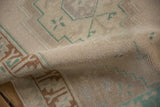 Evenly worn hand-knotted texture on a vintage rug in ivory, copper brown, and pale green.