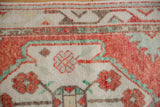 Hand-knotted texture of a distressed Turkish Oushak rug with cherry red and mint green blossoms.