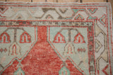 Evenly worn pile on a vintage Oushak rug showing corner patterns in cherry red, seafoam green, and ivory.