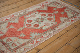 Distressed Oushak runner seen from an angle, with a cherry red medallion and pale seafoam green details.