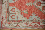 Worn pile on the corner spandrel of an Oushak rug, with tulip motifs in seafoam green and cherry red.