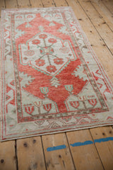 Angled view of the distressed Oushak runner, showing its low pile and soft red and ivory palette.
