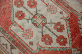 Close-up on the worn knot heads of a vintage Oushak with red blossoms and seafoam green accents.