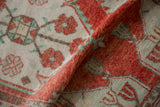 A folded vintage Oushak rug with time-softened texture in cherry red and pale seafoam green.