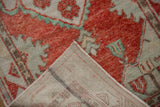 Folded corner of a vintage Oushak rug showing its hand-knotted back and low, distressed pile.