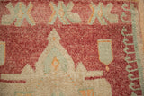 Faded raspberry, ivory, and slate blue geometric motifs on a distressed Kars rug.
