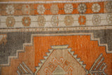 Distressed hand-knotted pile showing a stepped corner design in terracotta and silver.