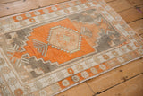 Angled view of a vintage distressed Oushak rug with a geometric terracotta and silver design.