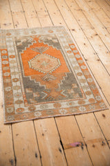 Angled view of a distressed Turkish Oushak rug with terracotta and silver geometric patterns.