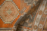 Folded vintage Oushak rug displaying the hand-knotted, low pile texture in terracotta and silver hues.